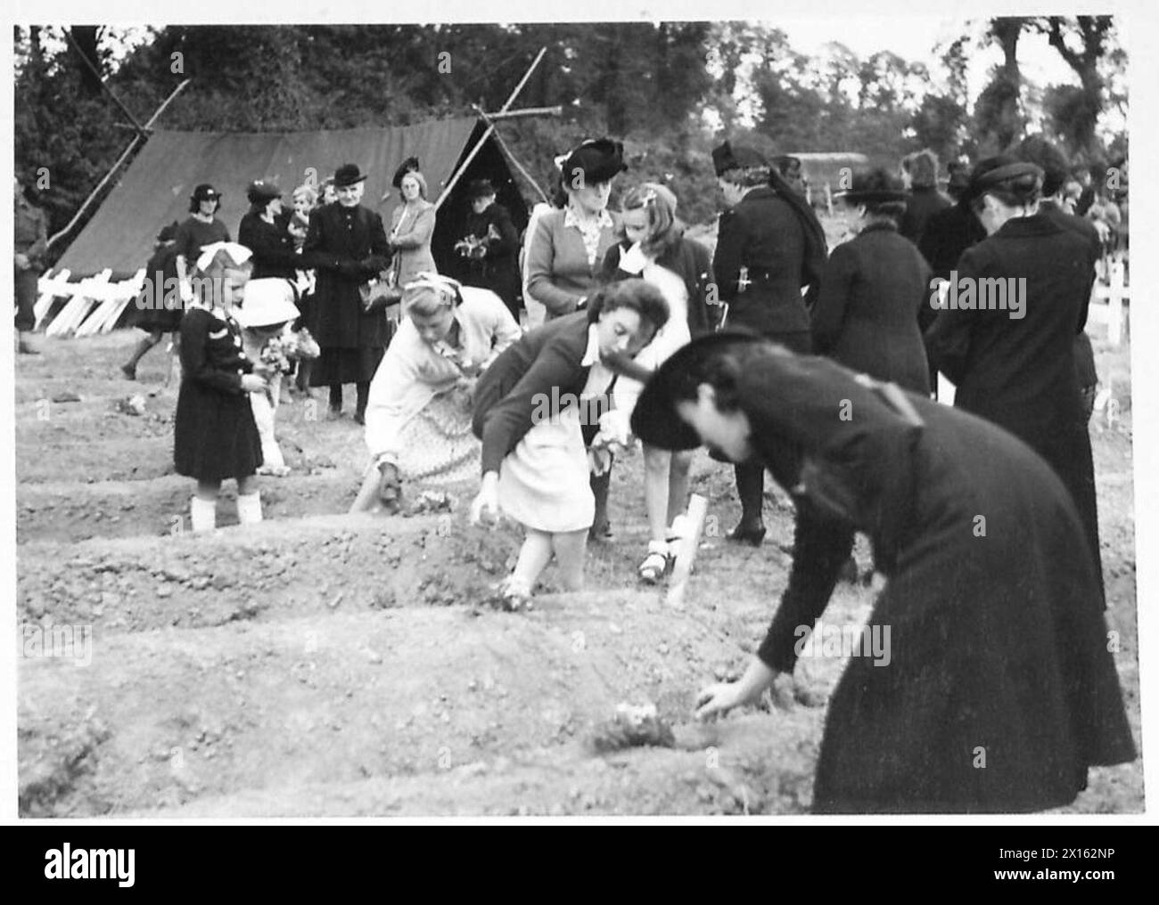 Des villageois de Normandie déposent des fleurs sur les tombes des soldats dans un cimetière pendant les commémorations du Bastille Day, British Army, 21st Army Group. Banque D'Images