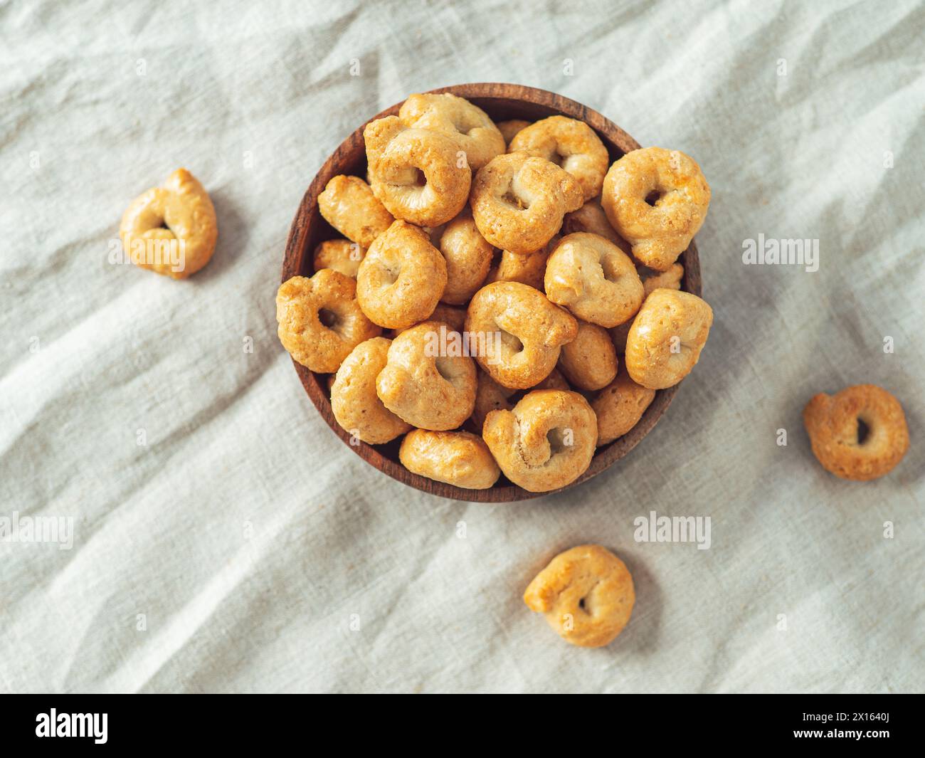 Snack italien traditionnel taralli ou tarallini dans un bol en bois sur fond de serviette en lin léger. Coup rustique de taralli hors-d'œuvre avec espace de copie. Vue de dessus ou à plat. Banque D'Images