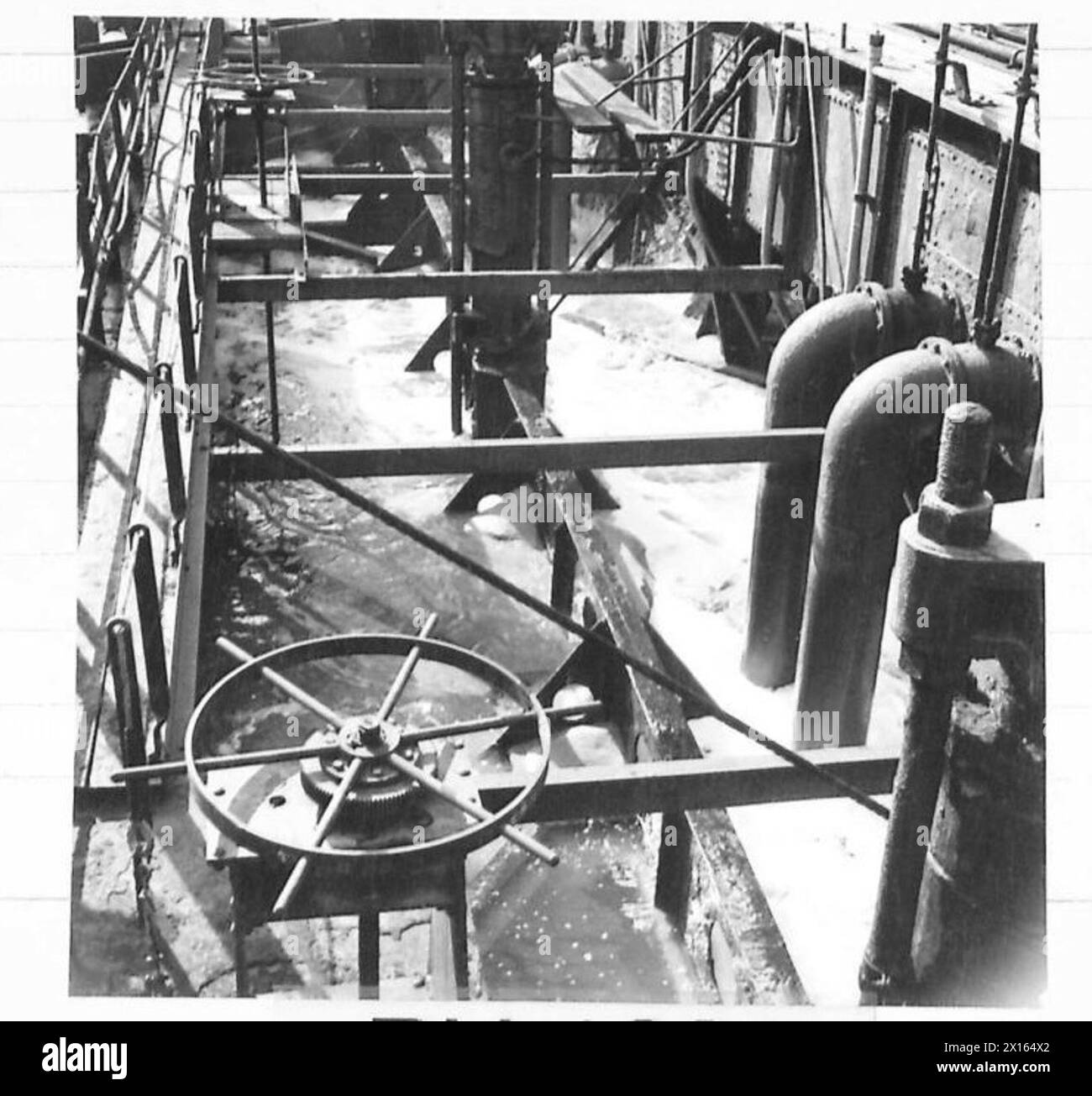 Les trémies à lisier d'une drague sont utilisées pour pomper du sable dans des unités brise-lames préfabriquées dans un port, documentées par le personnel de l'armée britannique. Banque D'Images