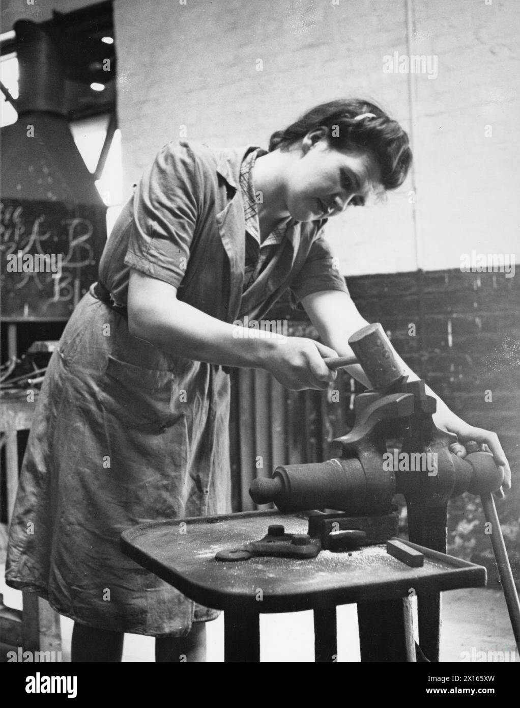 FORMATION POUR LE TRAVAIL DE GUERRE AU CENTRE DE FORMATION DU MINISTÈRE DU TRAVAIL DE CHELSEA POLYTECHNIC, LONDRES, ANGLETERRE, 1941 - Une stagiaire dans l'atelier d'essayage du Centre de formation du Ministère du travail de Chelsea Polytechnic plie la tôle dans le cadre de sa formation Banque D'Images