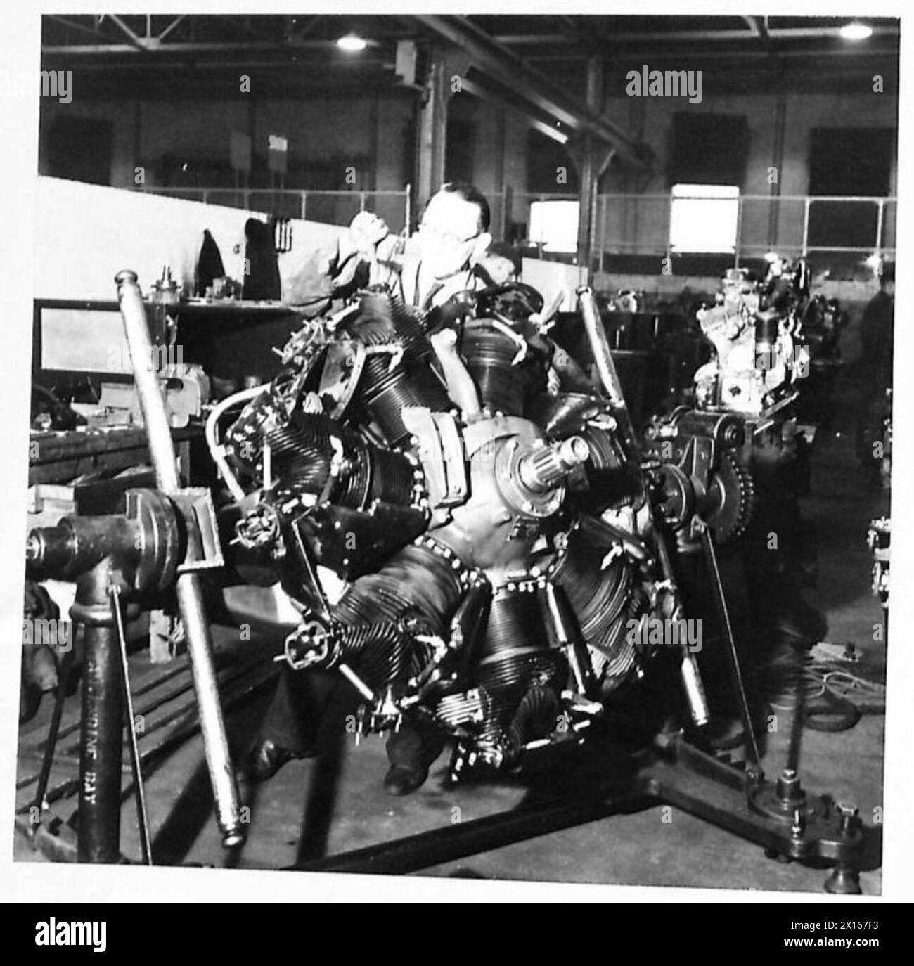 Un atelier féminin civil meule à la main des soupapes sur un bloc-cylindres de moteur d'avion radial Whirlwind fourni sous American Lend-Lease. Banque D'Images