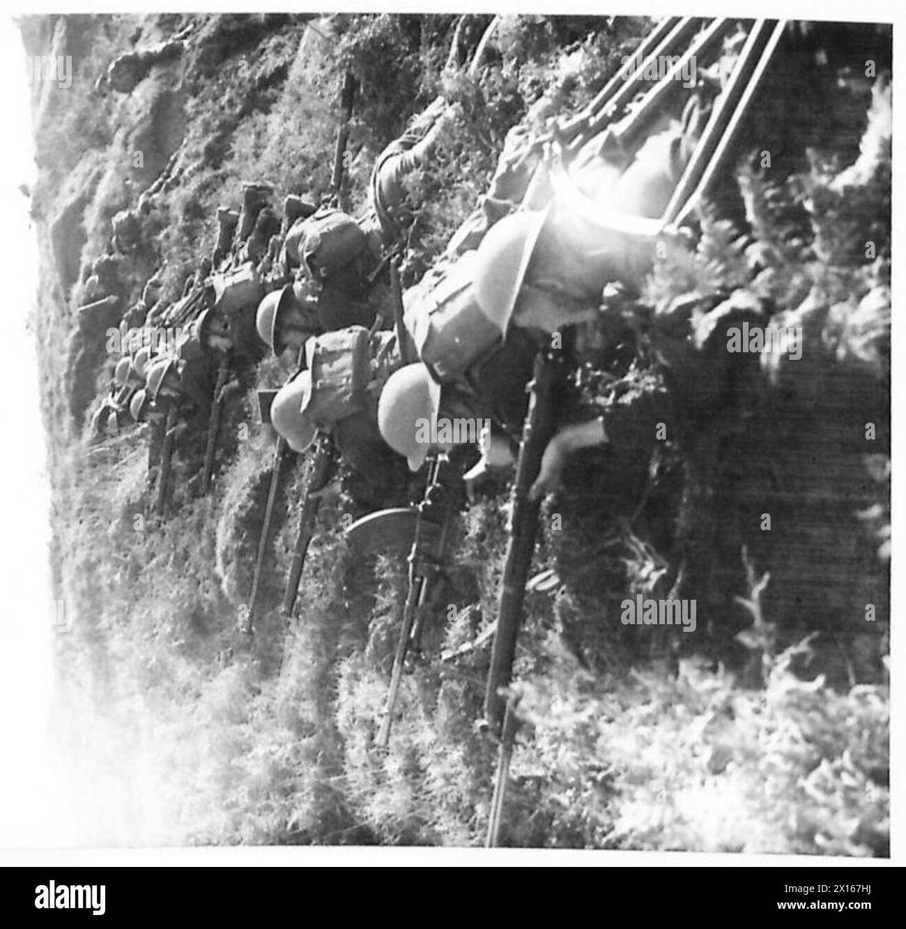 Une ligne de troupes irlandaises londoniennes atteint le sommet de la falaise avec des fusils, des canons Bren, et des fusils antichars de l'armée britannique. Banque D'Images