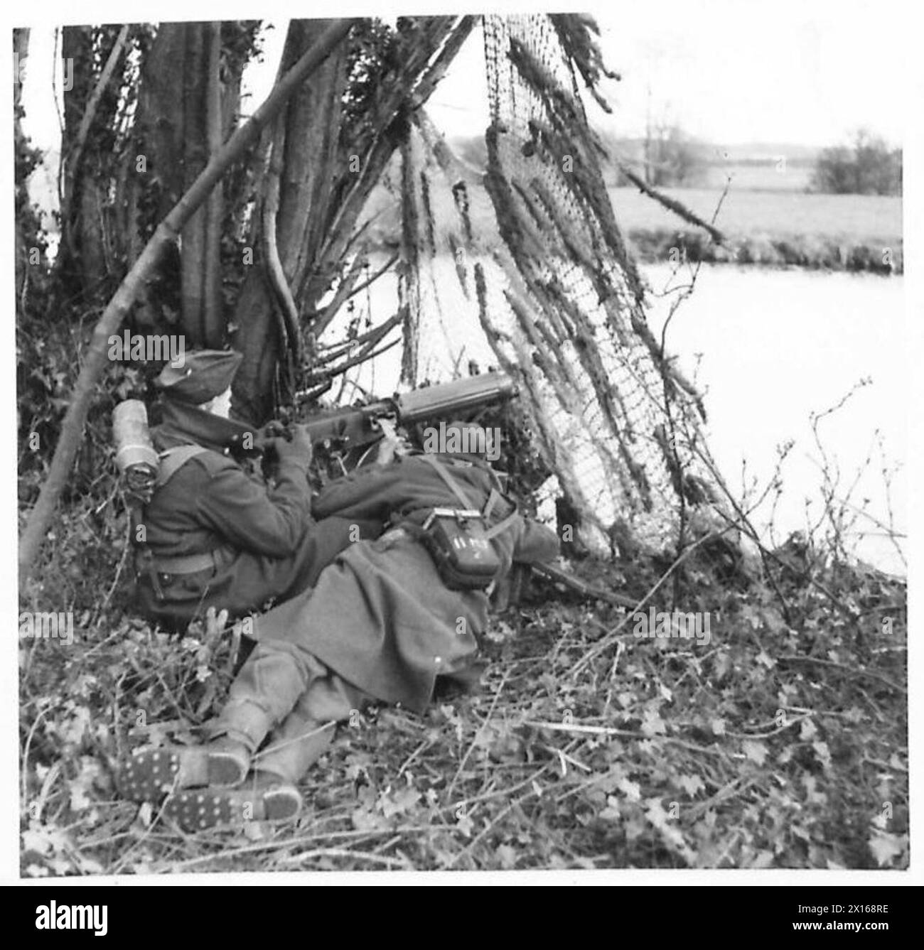 Les mitrailleuses des Coldstream Guards participent à une fausse bataille sur la rive d'une rivière à Fleet's Corner, Dorset. L'exercice démontre l'entraînement et la préparation des forces britanniques pendant la seconde Guerre mondiale. Banque D'Images