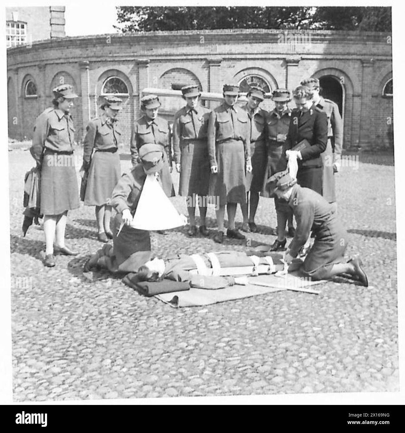 LE SERVICE DE TRANSPORT DES FEMMES [LA F.A.N.Y.] RECRUTE UNE FORMATION POUR FAIRE DU TRAVAIL EN S.E.A.C. - la connaissance des premiers soins est essentielle pour ces femmes qui vont faire un travail difficile. Nell Hitchon d'Ilkey, Yorks, qui a été matrone dans une école de garçons, pratique un habillage compliqué, tandis qu'Ethelwynne Brutnell d'Eastbourne, qui a 4 1/2 ans d'expérience en tant que chauffeur d'ambulance, prépare le bandage pour elle. Leur instructeur, la divisionnaire Lady Superintendent G.M. Langford, British Red Cross Society, a vécu à l'est et est, par conséquent, en mesure de préparer les recrues aux problèmes particuliers de la Banque D'Images