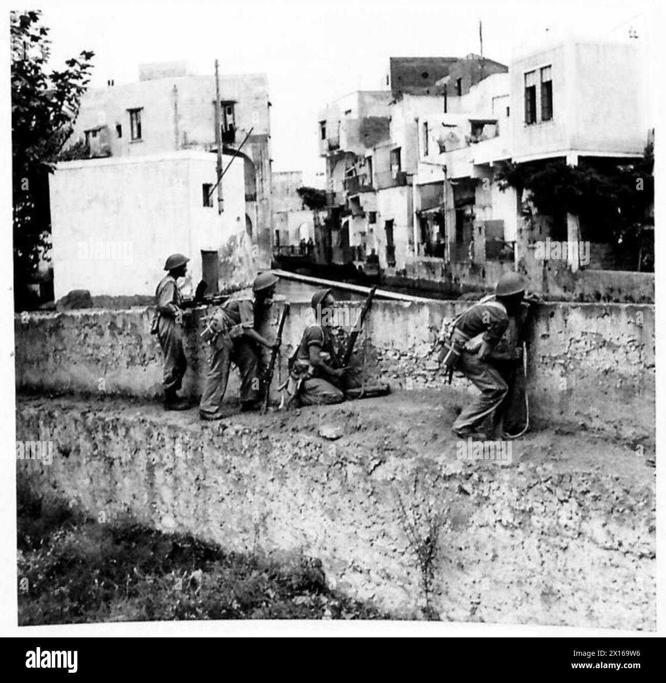 Les hommes du 1/6 Queen's Regiment capturent la ville de Scafati, avançant le long d'une rivière avec les forces ennemies dans des maisons sur la rive opposée. Banque D'Images