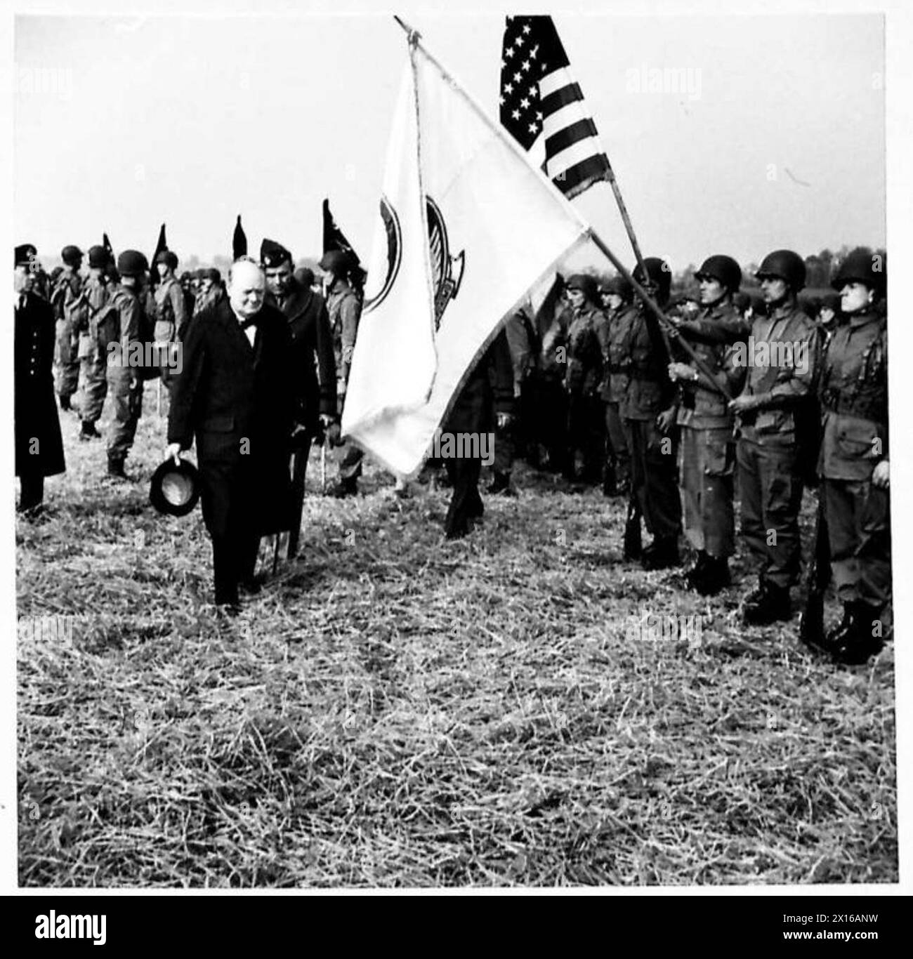 Le premier ministre inspecte les parachutistes américains en défilé, saluant le drapeau national « Old Glory ». Le personnel de l'armée britannique est présent lors de l'inspection cérémonielle. Banque D'Images