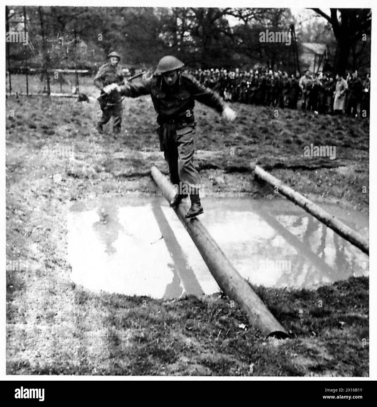 Les concurrents traversent un pont de corde au-dessus d'un ruisseau dans le cadre d'une compétition de course d'assaut lors d'une réunion sportive militaire. Banque D'Images