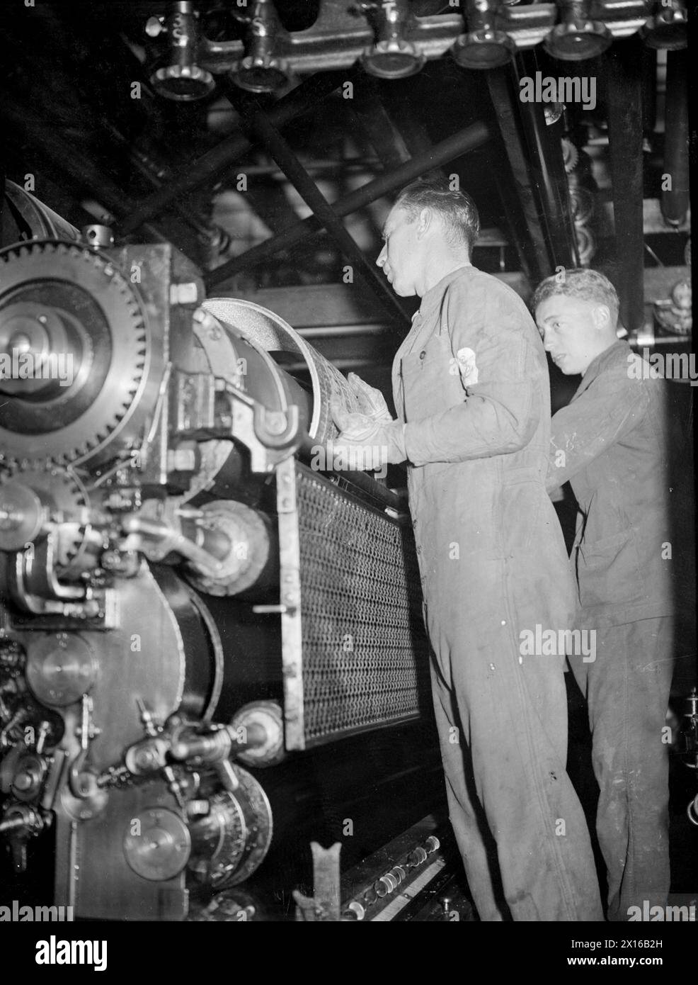 En août 1945, la British Pacific Fleet produit et distribue son journal Pacific Post à Sydney. Le matelot principal Wm F. Daniels et le matelot Able Francis Hayes utilisaient une presse rotative à houe dans la salle des machines. Banque D'Images