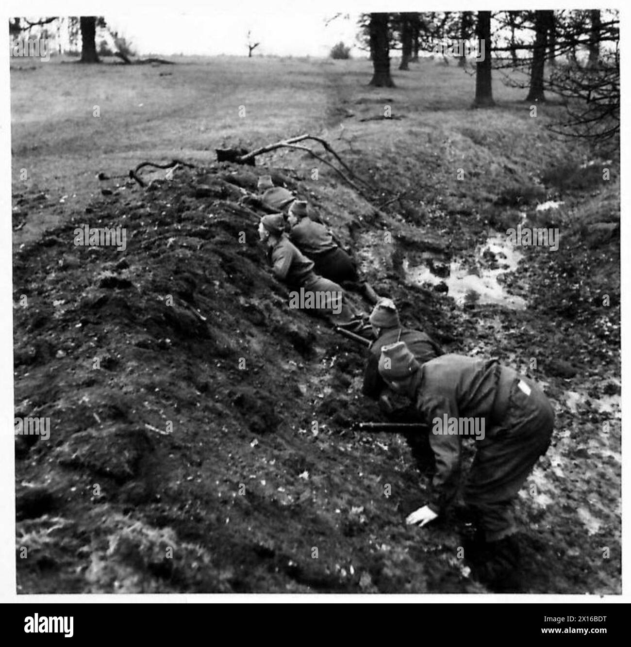 Une patrouille se met à l'abri dans un fossé tandis que des correspondants de guerre observent lors d'une visite au Commandement de l'est. Banque D'Images