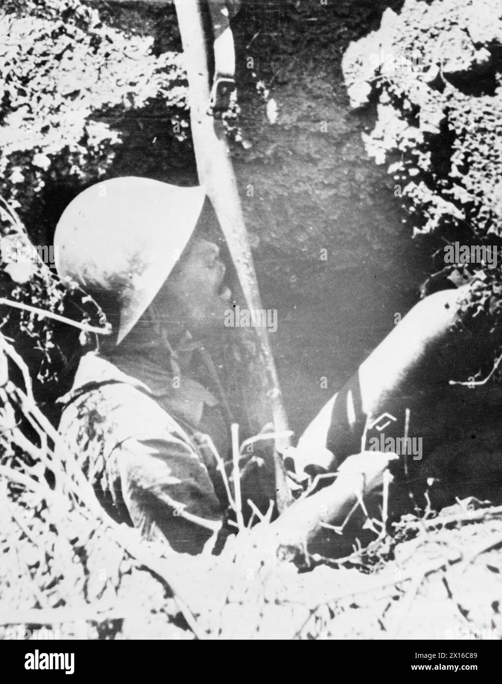 MINES ANTICHARS HUMAINES EN BIRMANIE - des soldats japonais retranchés dans des trous de la route de Pegu avec des bombes aériennes de 100 lb entre leurs genoux ont été découverts par une colonne blindée britannique conduisant vers le sud. Cette image montre un soldat de ce type, qui tient également une pièce d'acier avec laquelle faire exploser sa bombe. Il a été tué par un tir de fusil britannique Banque D'Images