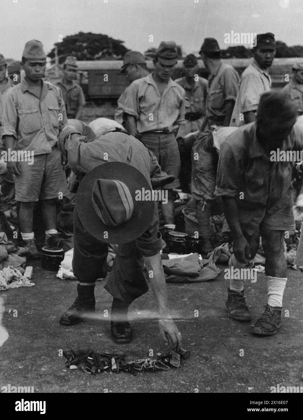 Un officier britannique Gurkha inspecta des couteaux, des aiguilles et des rasoirs confisqués à des soldats japonais désarmés à la gare de Bangkok avant leur transfert dans des camps de prisonniers de guerre en 1945. Banque D'Images