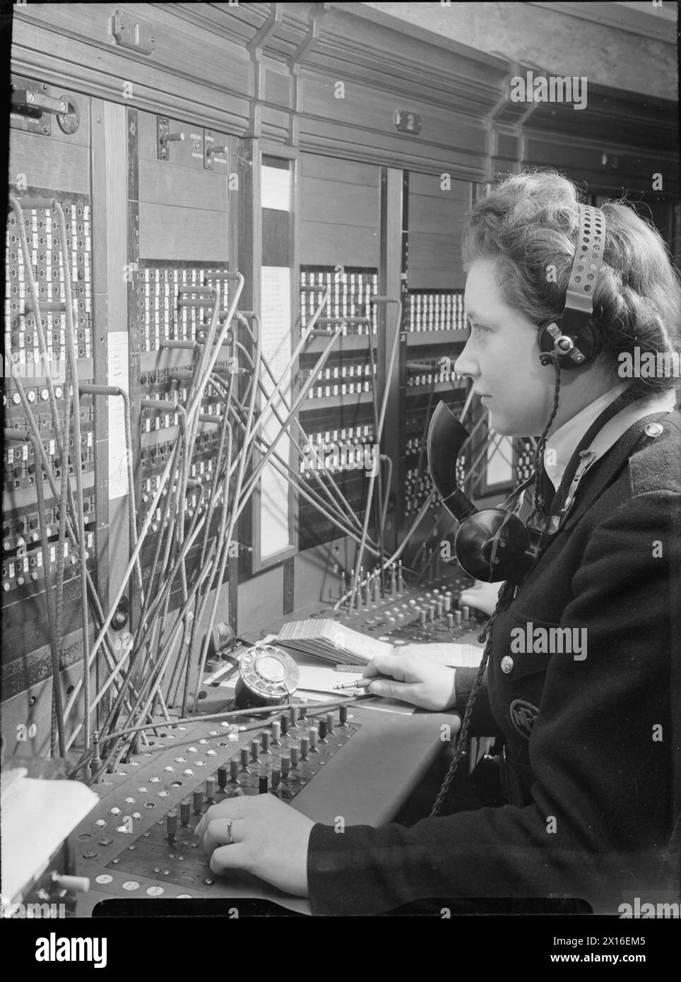 Un opérateur de tableau de commutation du Service national des incendies gère les communications à l'administration centrale de la région de London en 1944, coordonnant les rapports d'incendie et les ordres opérationnels pendant les urgences en cas d'incendie. Banque D'Images