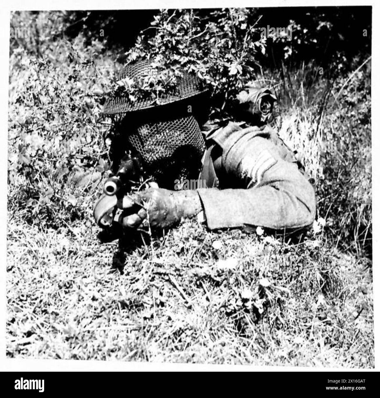 Un soldat de l'armée britannique camouflé parmi les buissons vise avec un pistolet Tommy lors d'un exercice d'entraînement. Banque D'Images
