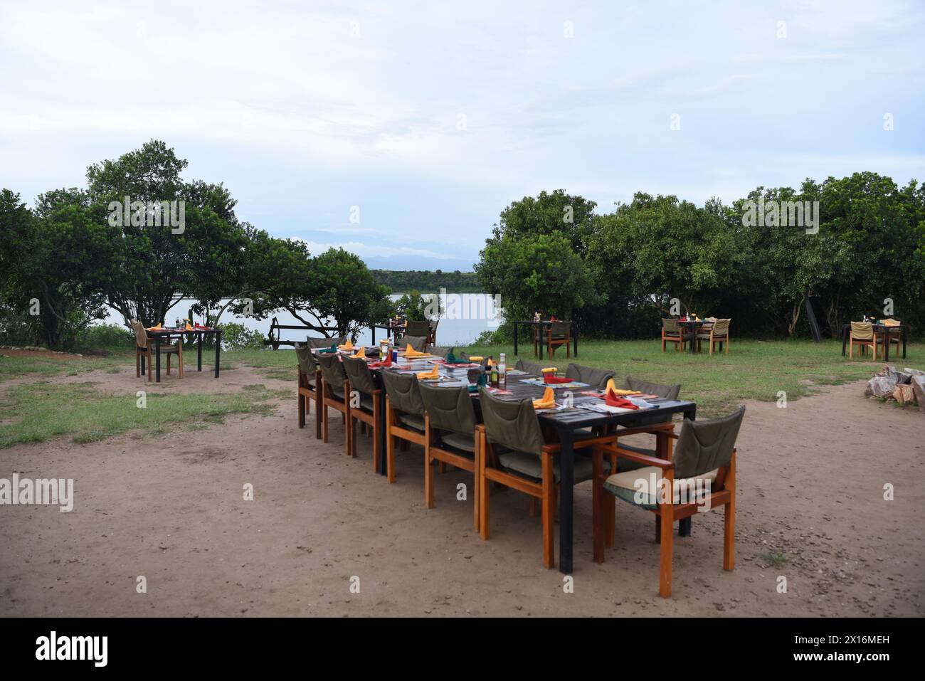 Sous la canopée de la végétation luxuriante du parc national de Kibale, des tables élégamment agencées attendent les convives, ornées de chandelles scintillantes et d'une ambiance vibrante Banque D'Images