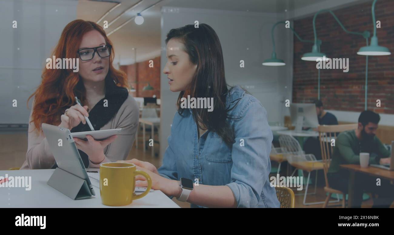 Image de gens marchant sur deux femmes d'affaires caucasiennes utilisant la tablette Banque D'Images