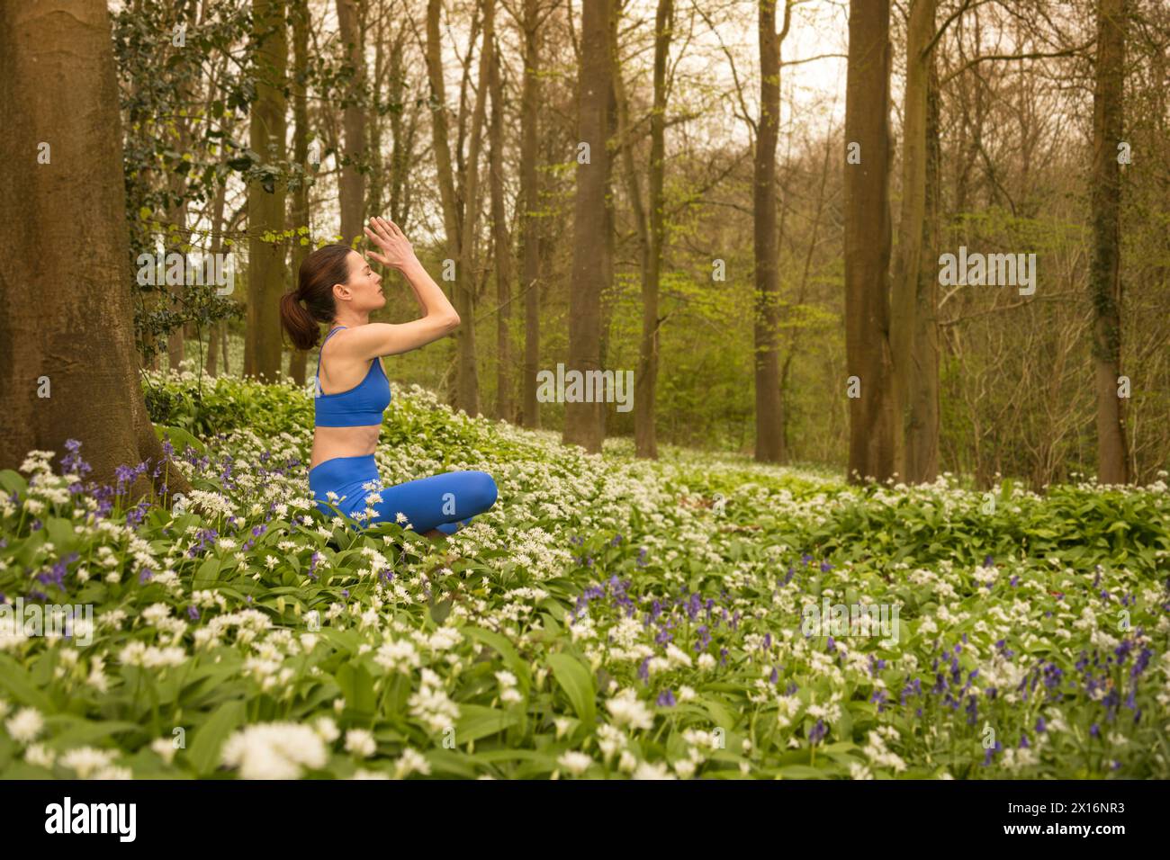 femme méditant dans la nature, l'ail sauvage et bluebell prairie et la forêt. Printemps, concept de remise en forme estivale. Banque D'Images