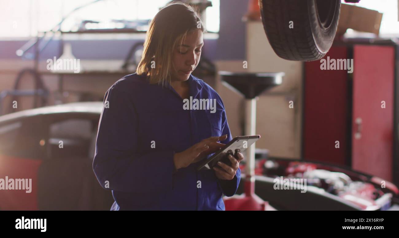 Image de lumière incandescente sur une femme biraciale travaillant dans un atelier de voiture. Petite entreprise, finance, informatique et concept de traitement des données généré numériquement Banque D'Images