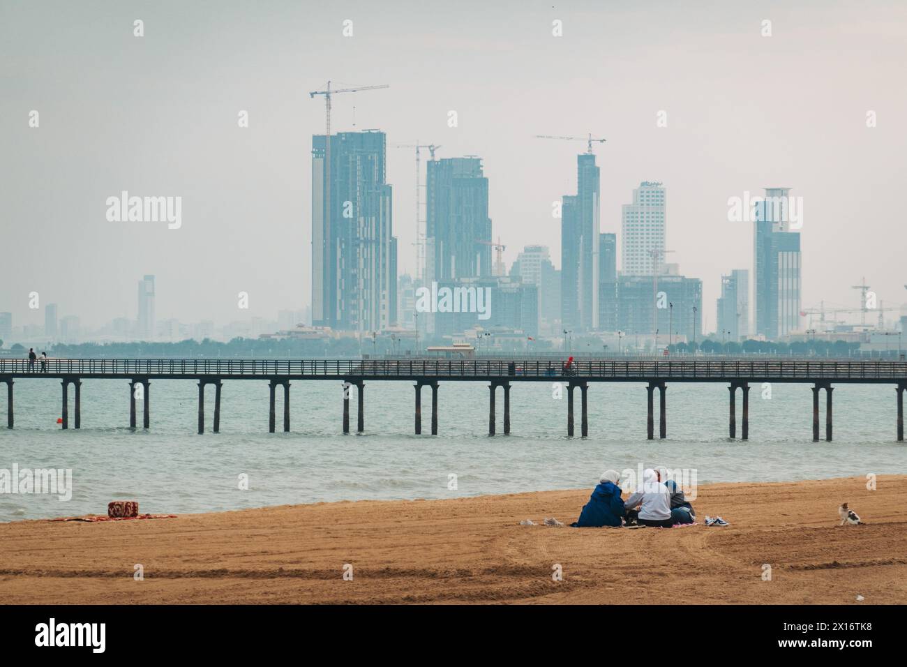Trois femmes pique-niquent sur Towers Beach, Kuwait City, Koweït. Nouvelle construction de grande hauteur visible en arrière-plan Banque D'Images