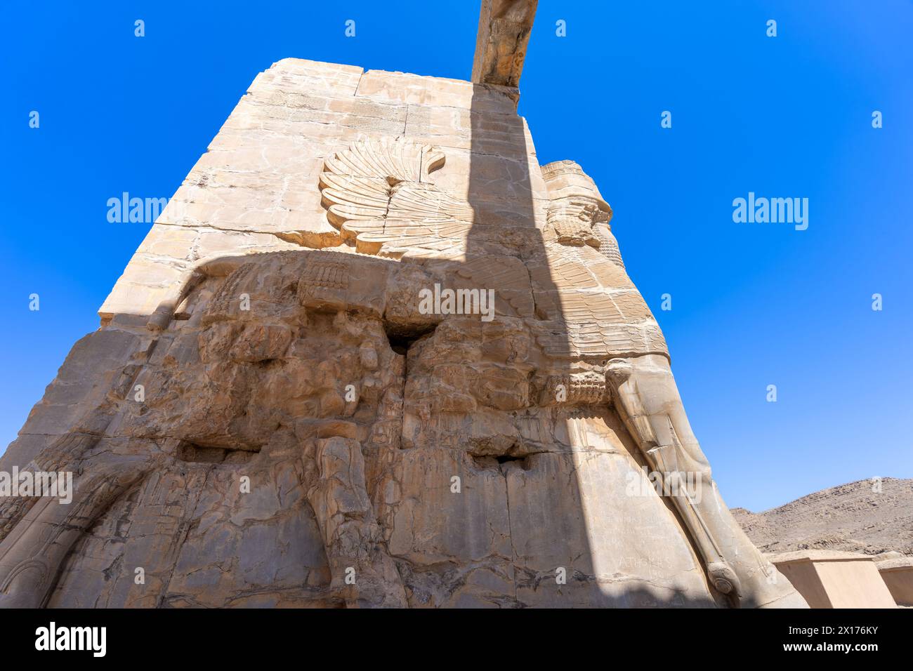 Imposantes statues Lamassu se dressent en hauteur, projetant des ombres complexes au milieu des ruines antiques de Persépolis, en Iran. Capturé par un jour lumineux avec le SK bleu Banque D'Images