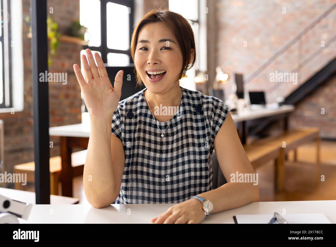 Femme professionnelle mature asiatique ondulant, assise au bureau dans un bureau d'affaires moderne sur appel vidéo Banque D'Images