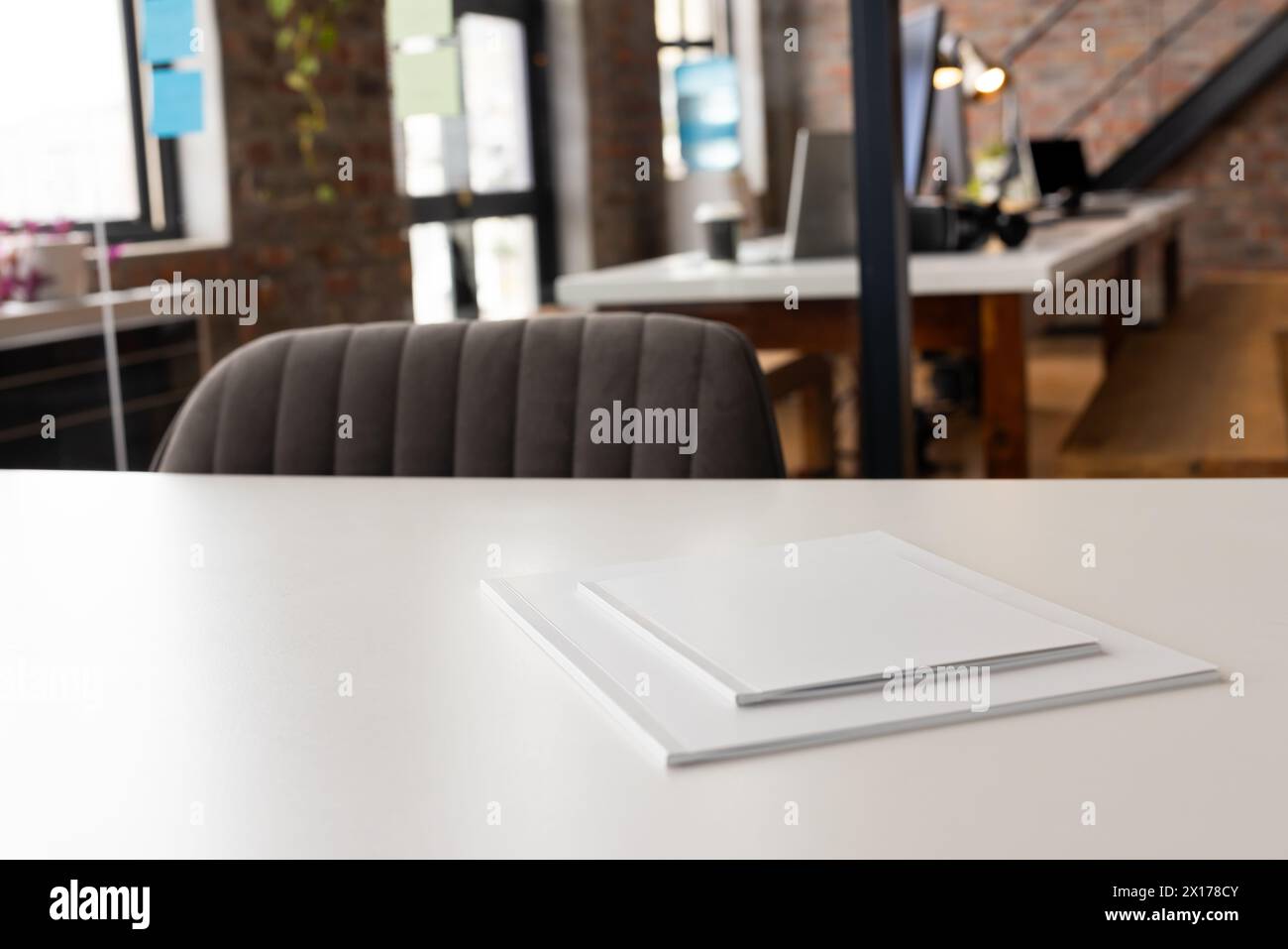 Espace de bureau vide avec bureau blanc au centre, papiers reposant sur le dessus Banque D'Images