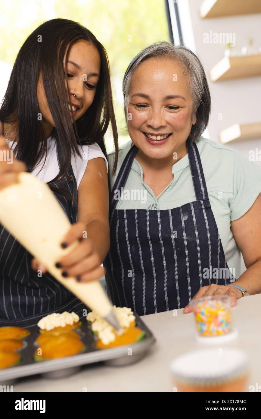 La grand-mère asiatique et la petite-fille adolescente biraciale cuisent ensemble à la maison Banque D'Images