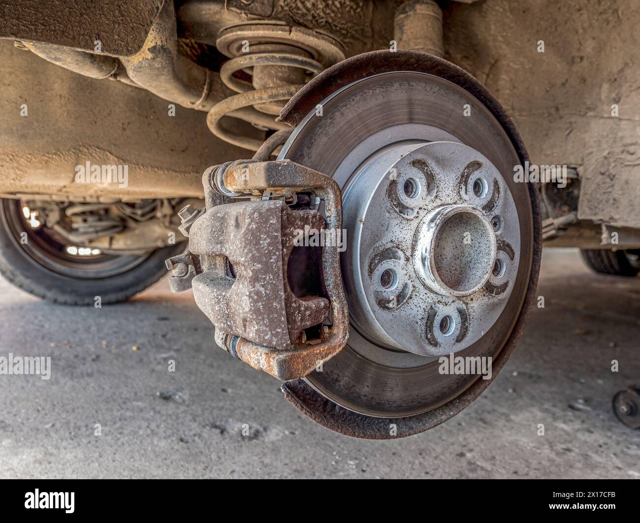 Véhicule de tourisme sur un pont élévateur avec le pneu arrière déposé exposant le disque de frein Banque D'Images