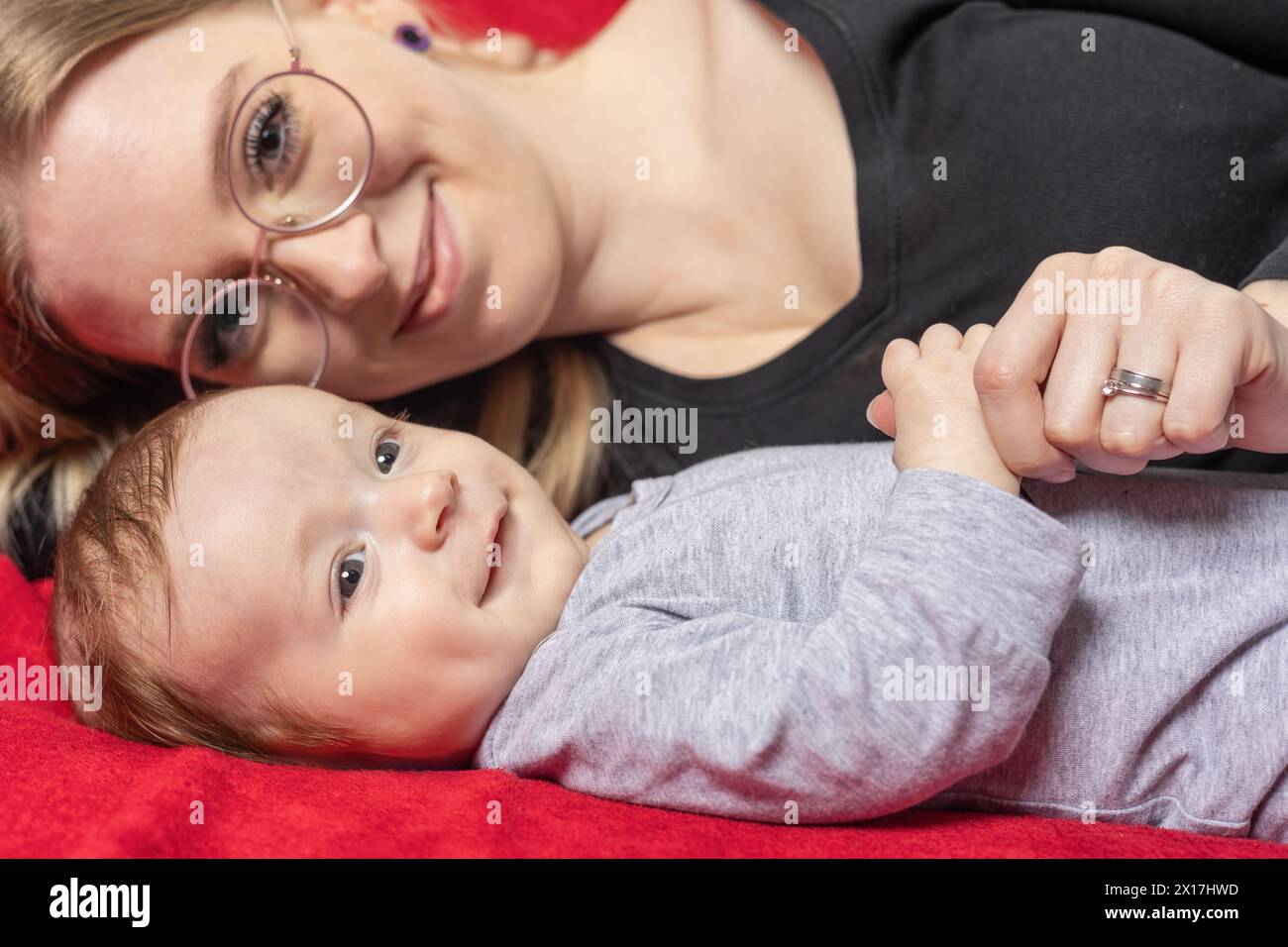La mère souriante est allongée avec son nouveau-né garçon regardant la caméra. Horizontalement. Banque D'Images