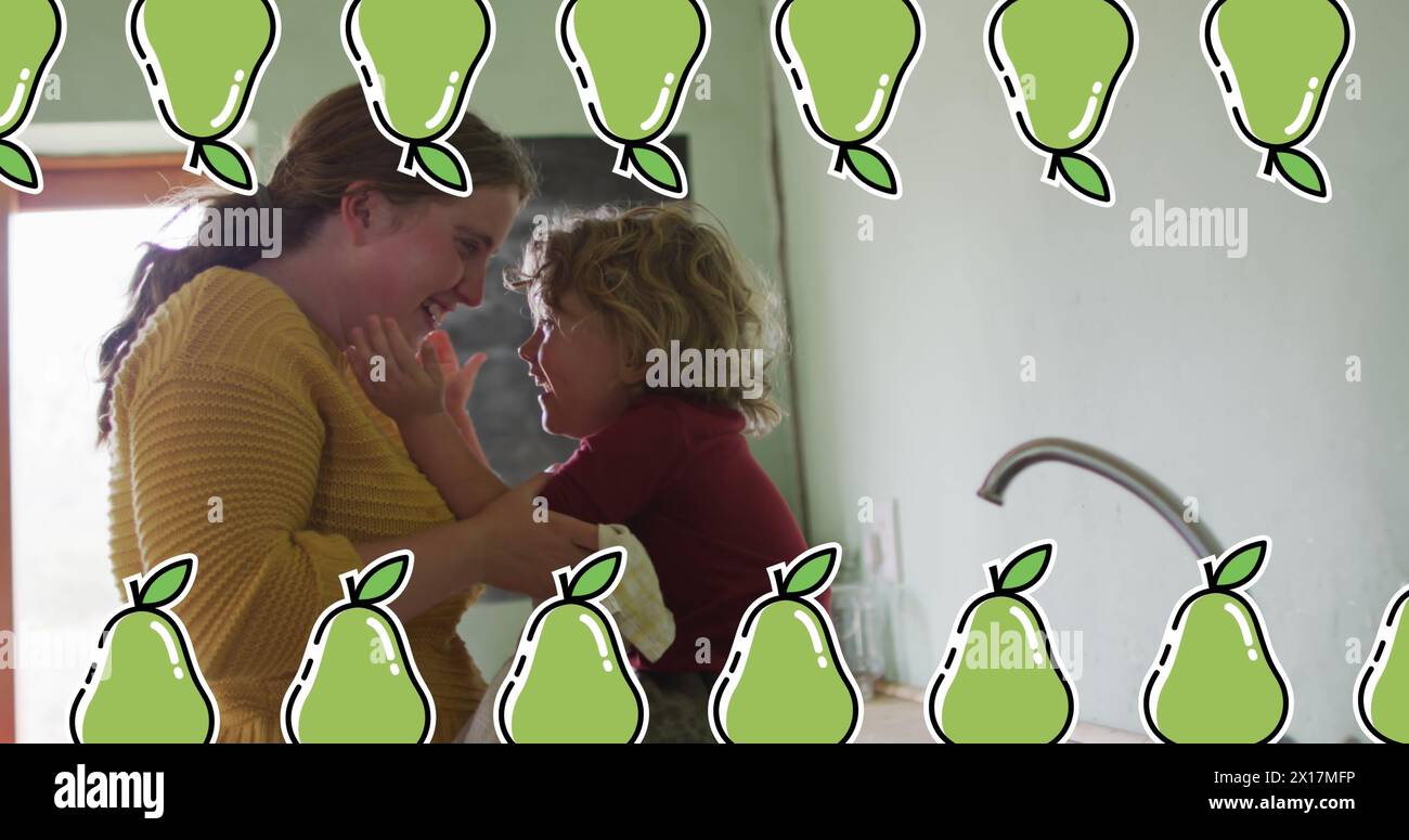 Image d'icônes de poire sur une femme caucasienne avec son fils dans la cuisine Banque D'Images