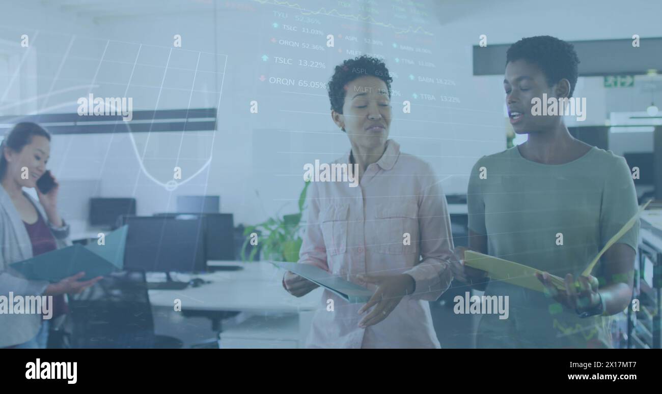 Image du traitement des données boursières sur deux femmes diverses discutant tout en marchant au bureau Banque D'Images
