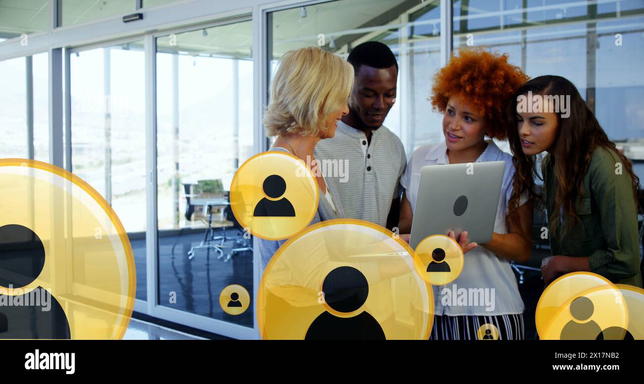 Image de plusieurs icônes de profil au-dessus de plusieurs collègues discutant des rapports sur un ordinateur portable au bureau Banque D'Images