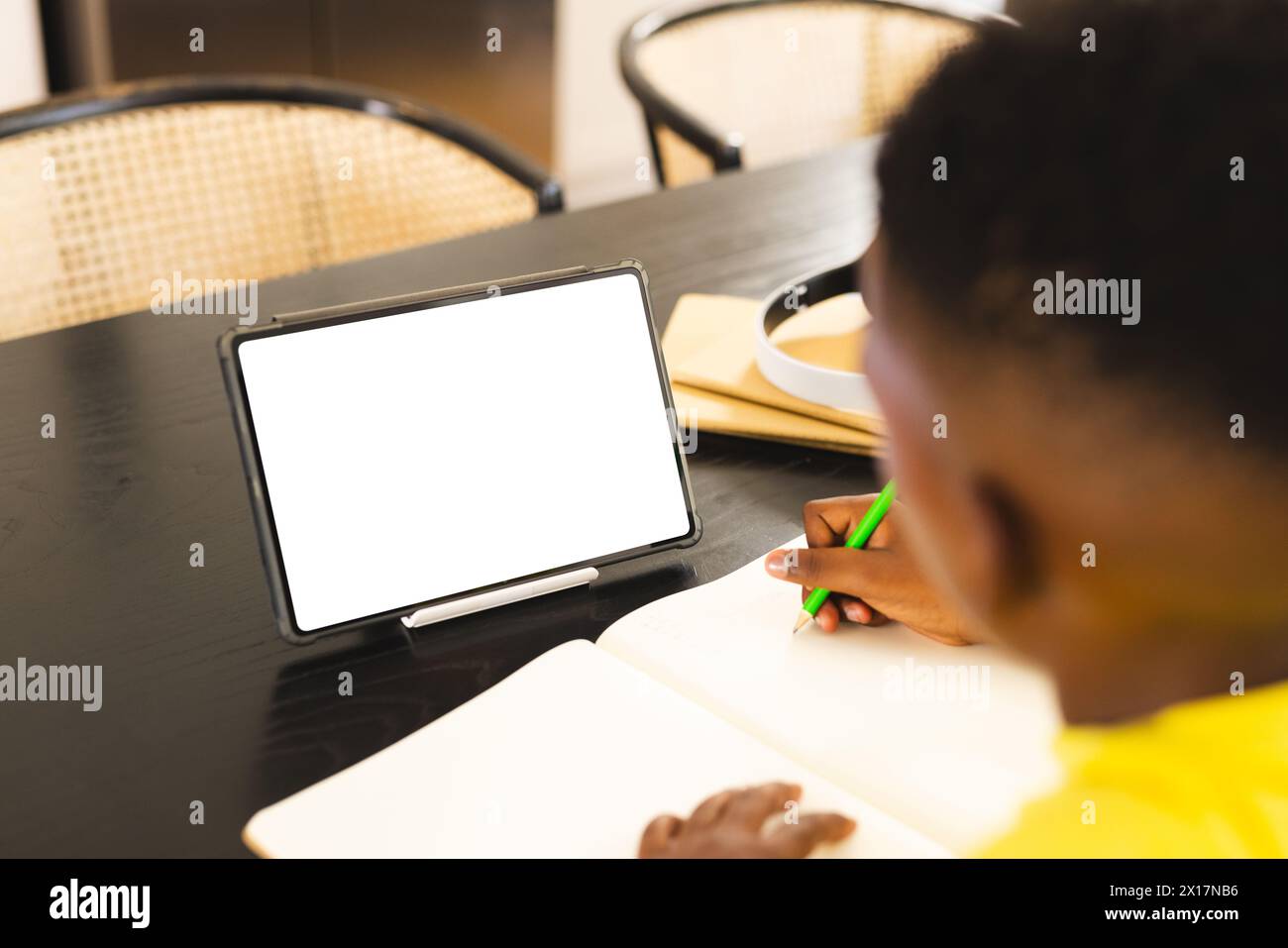 Garçon afro-américain portant une chemise jaune dessine à côté d'une tablette à la maison avec un espace de copie Banque D'Images