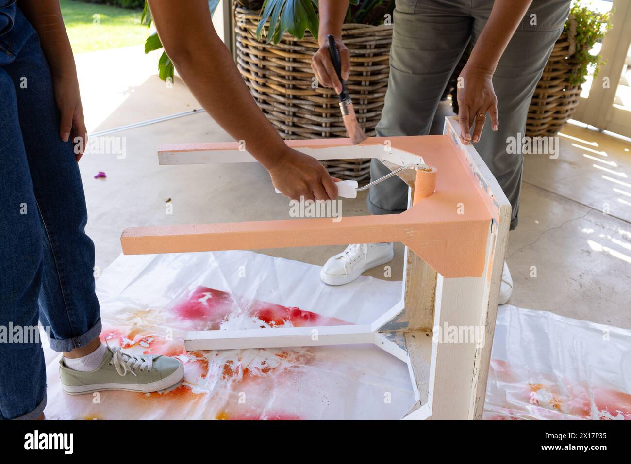 Mère biraciale et fille adulte peignent une table ensemble à la maison dans le cadre d'un projet d'upcycling Banque D'Images