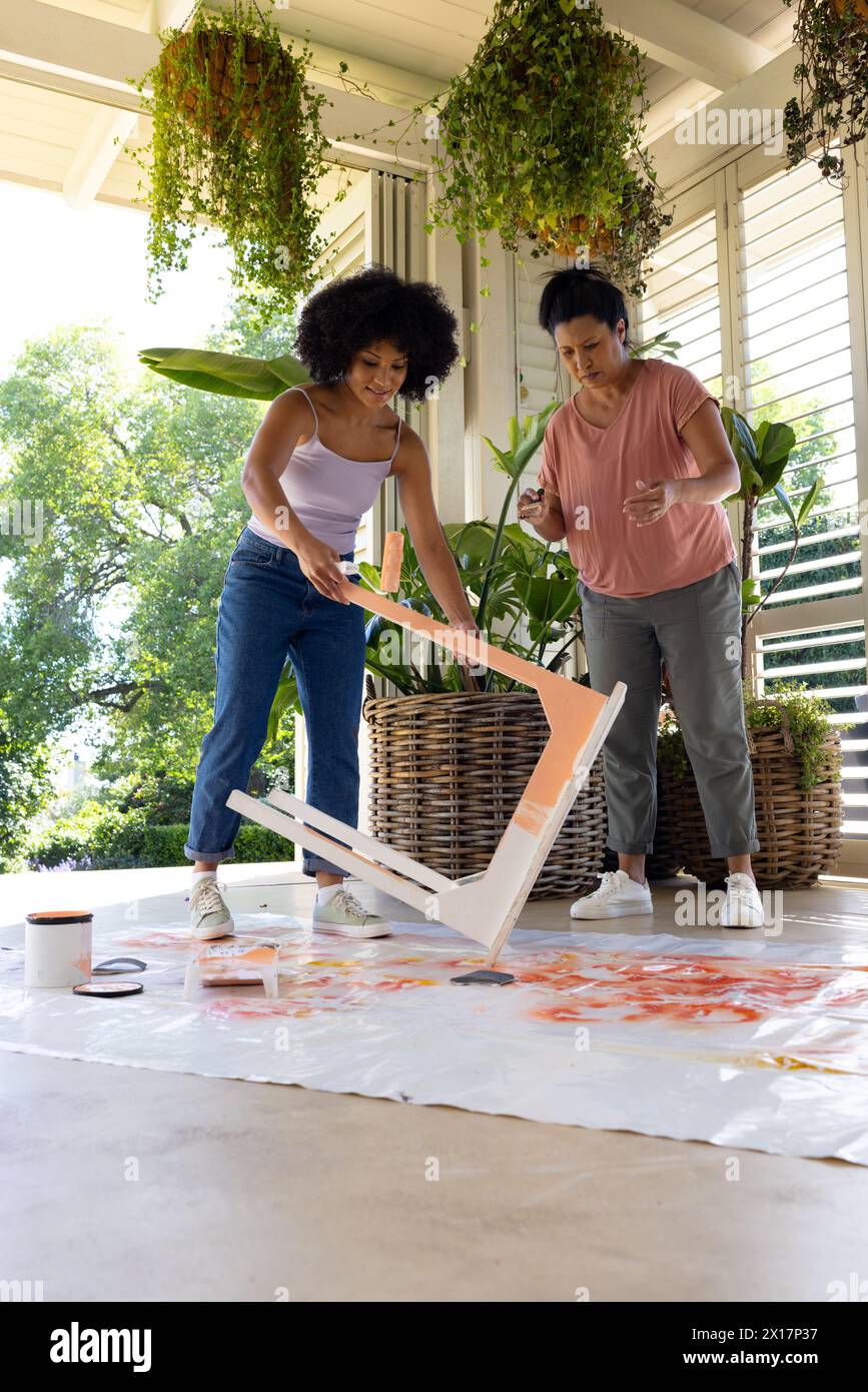 Mère biraciale et fille adulte peignent des meubles ensemble à la maison pour un projet d'upcycling Banque D'Images