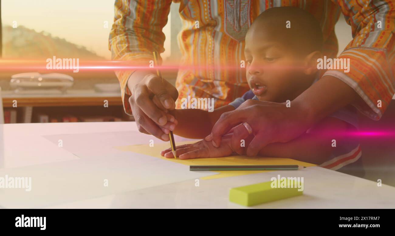 Image de lumière clignotante sur le père afro-américain et son fils dessinant la main sur le papier Banque D'Images