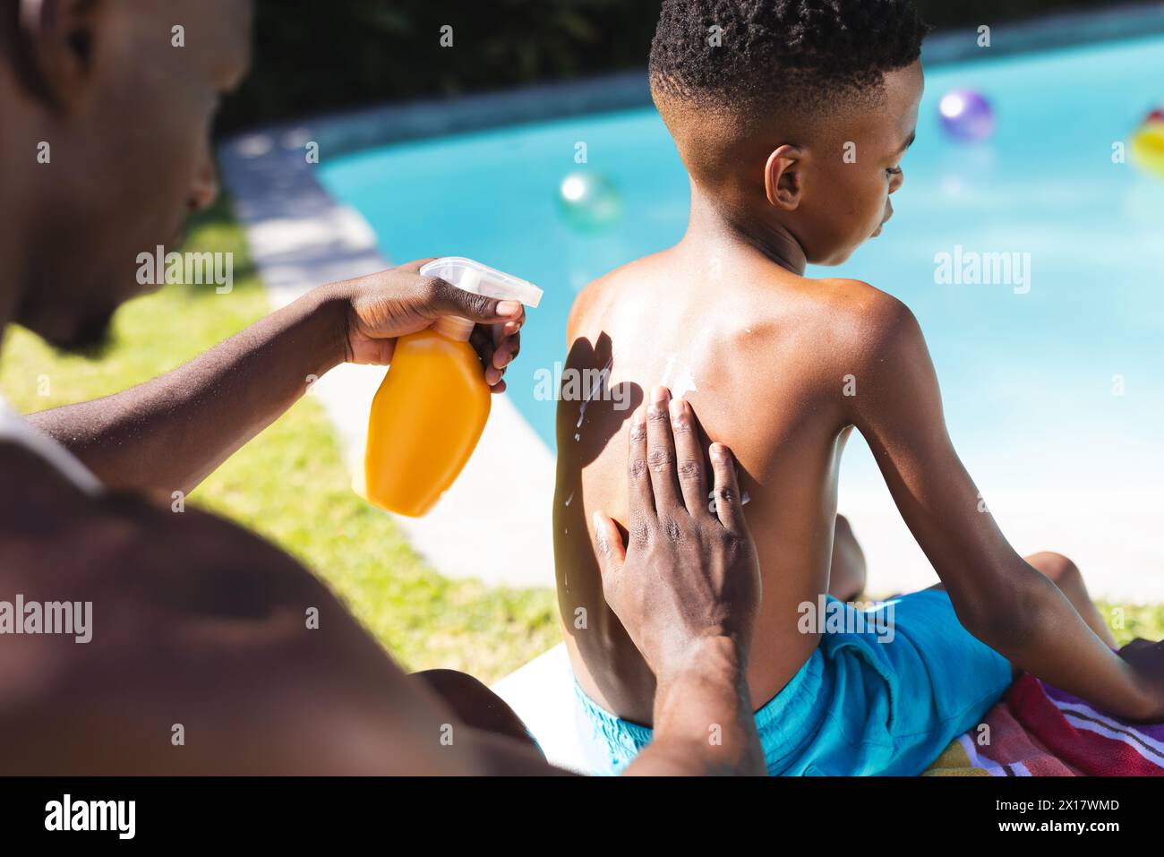 Père afro-américain appliquant de la crème solaire sur le dos de son fils à la maison Banque D'Images