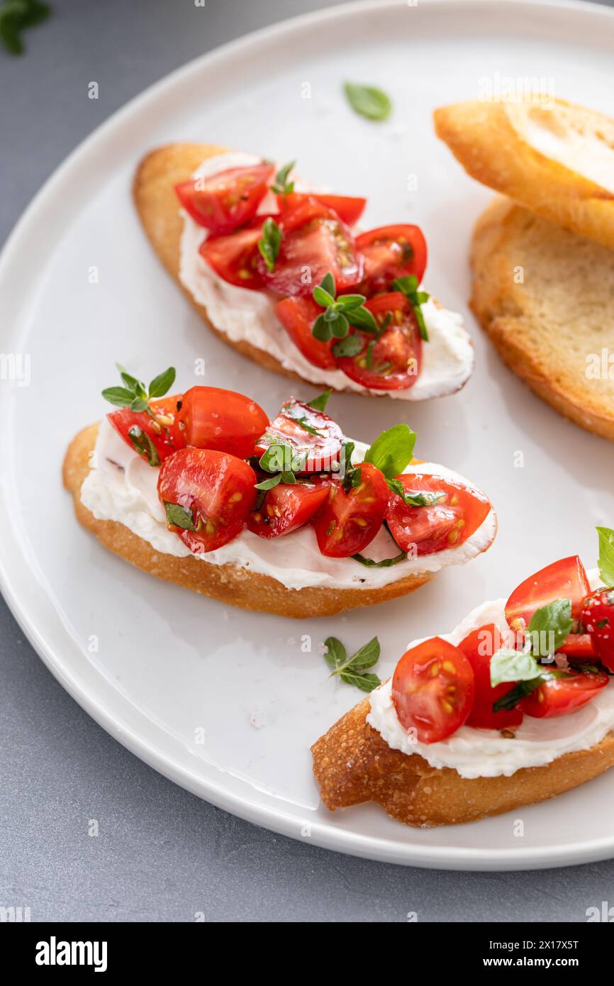 Préparation de crostini ou bruschetta au basilic tomate avec baguette grillée et fromage à la crème Banque D'Images