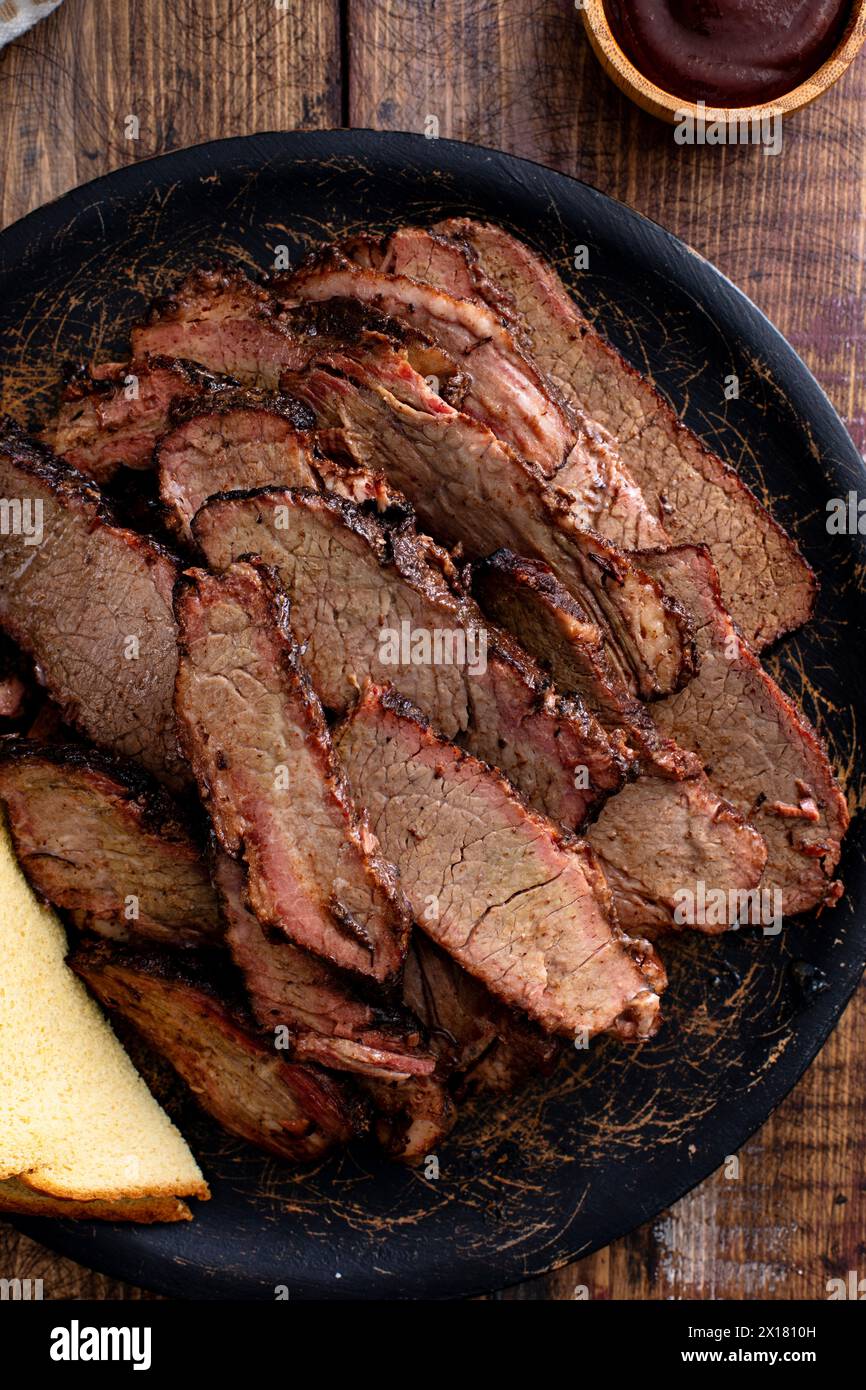 Poitrine de boeuf fumé tranchée sur l'assiette de service avec pain grillé et sauce barbecue Banque D'Images