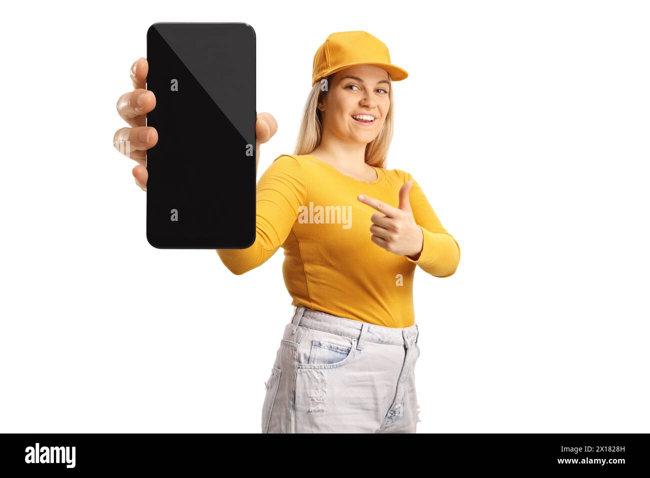 Jeune femme avec une casquette tenant un smartphone et pointant isolé sur fond blanc Banque D'Images