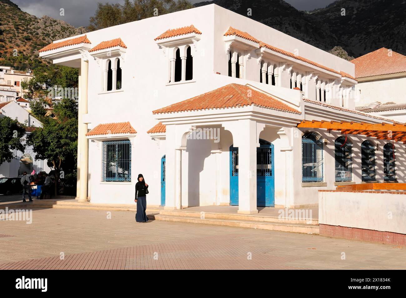 Bâtiment administratif, Chefchaouen, Un bâtiment blanc ensoleillé avec des volets bleus contre une montagne et un ciel bleu, Chefchaouen, Maroc Banque D'Images