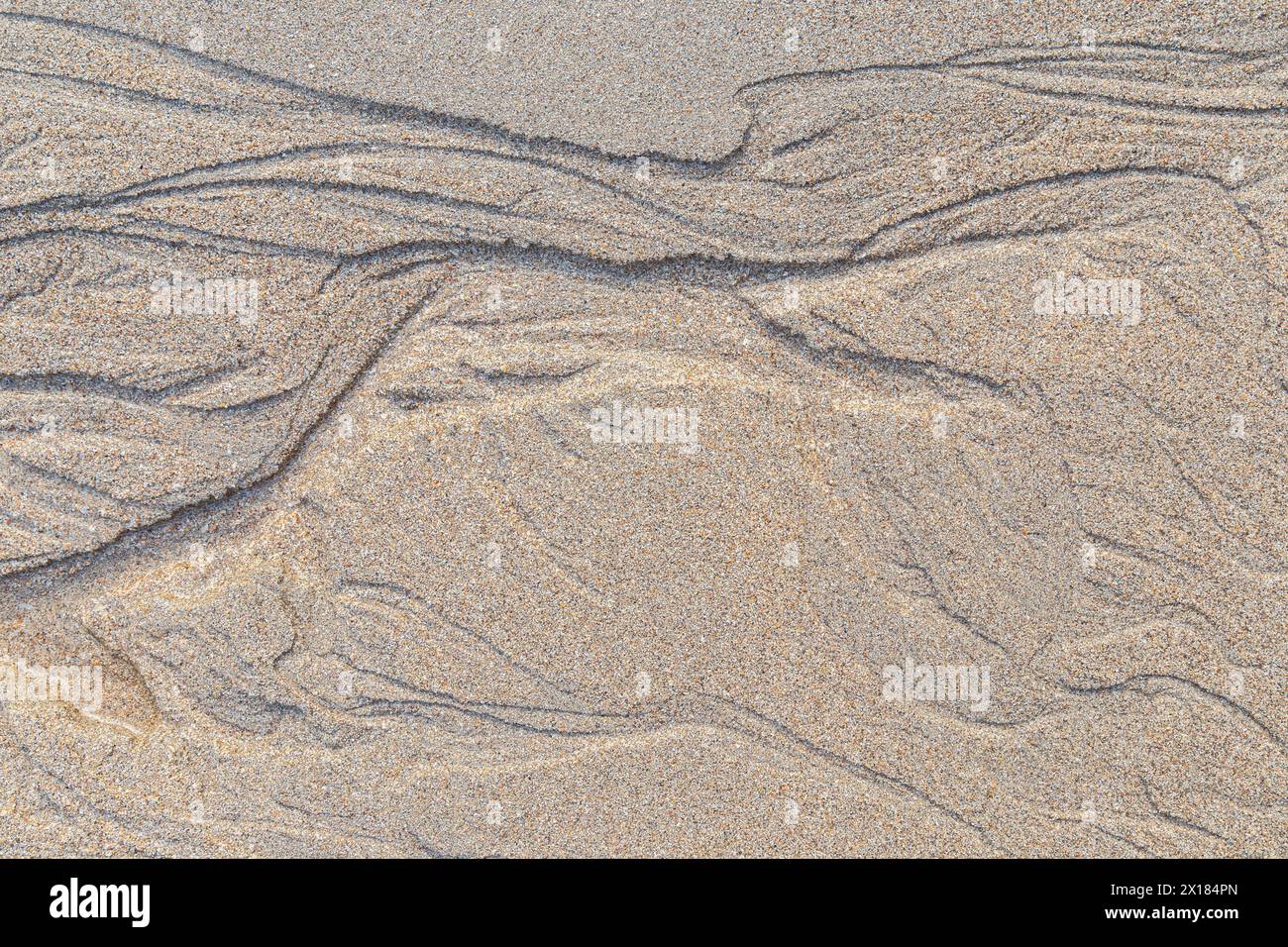 Formes abstraites et motifs dans le sable granuleux sur la plage par une journée ensoleillée, vue d'en haut. Fond de sable naturel texturé abstrait, vue de dessus. Banque D'Images