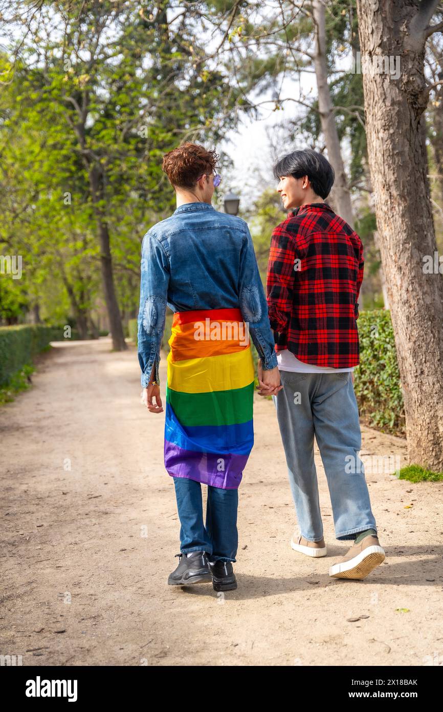 Vue arrière verticale pleine longueur d'un couple gay marchant le long d'un parc Banque D'Images