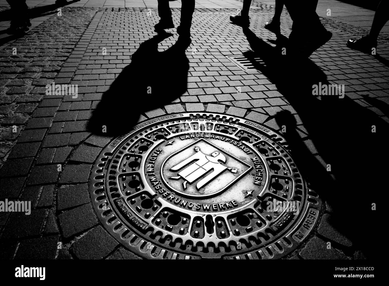 Muenchner Kindl sur un couvercle de trou d'homme dans la zone piétonne, Munich, Bavière, Allemagne Banque D'Images