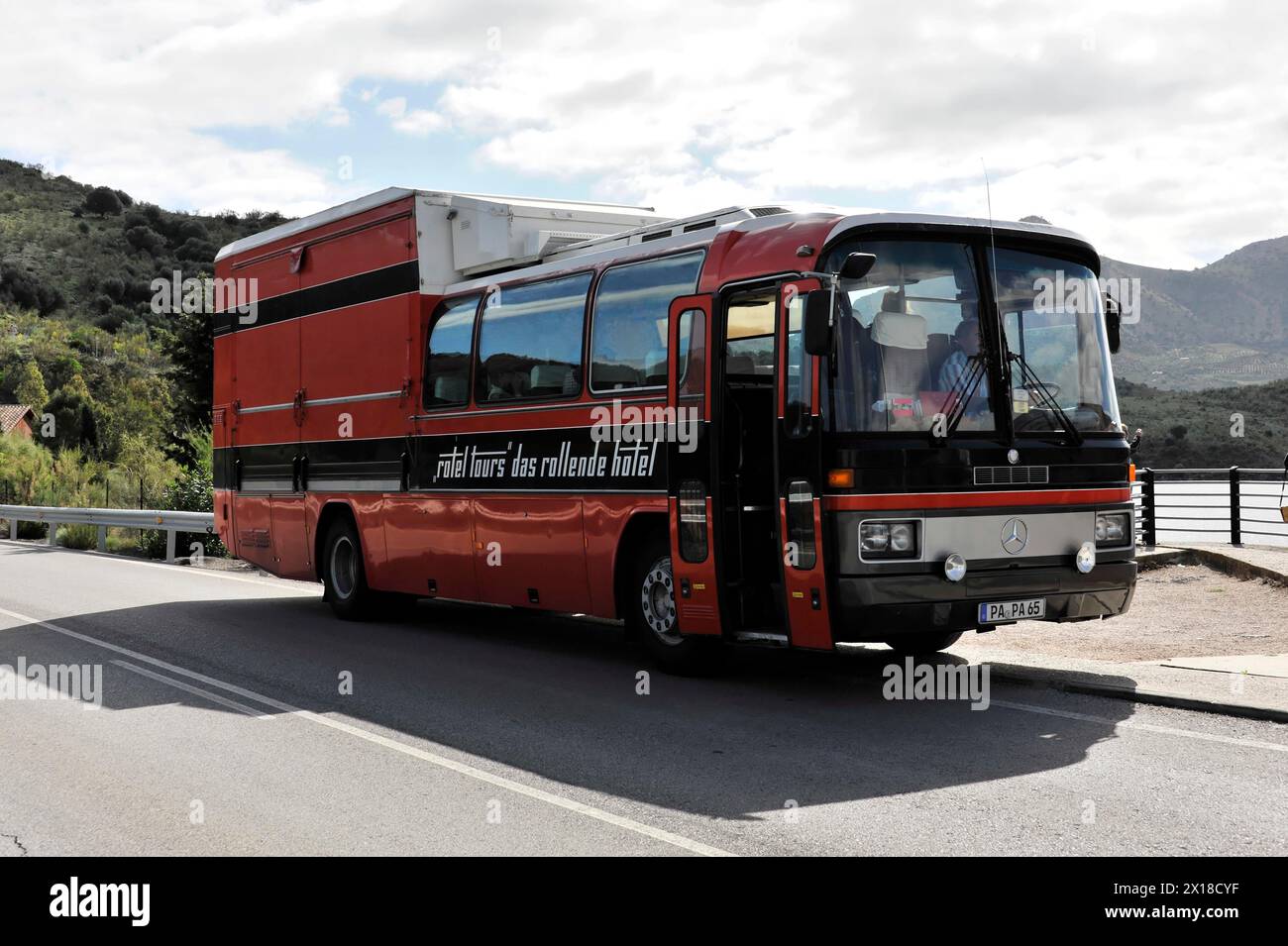 Près d'Arcos, bus rouge au bord de la route avec l'inscription 'Rolling Hotel' en face d'une montagne en toile de fond, Andalousie, Espagne Banque D'Images