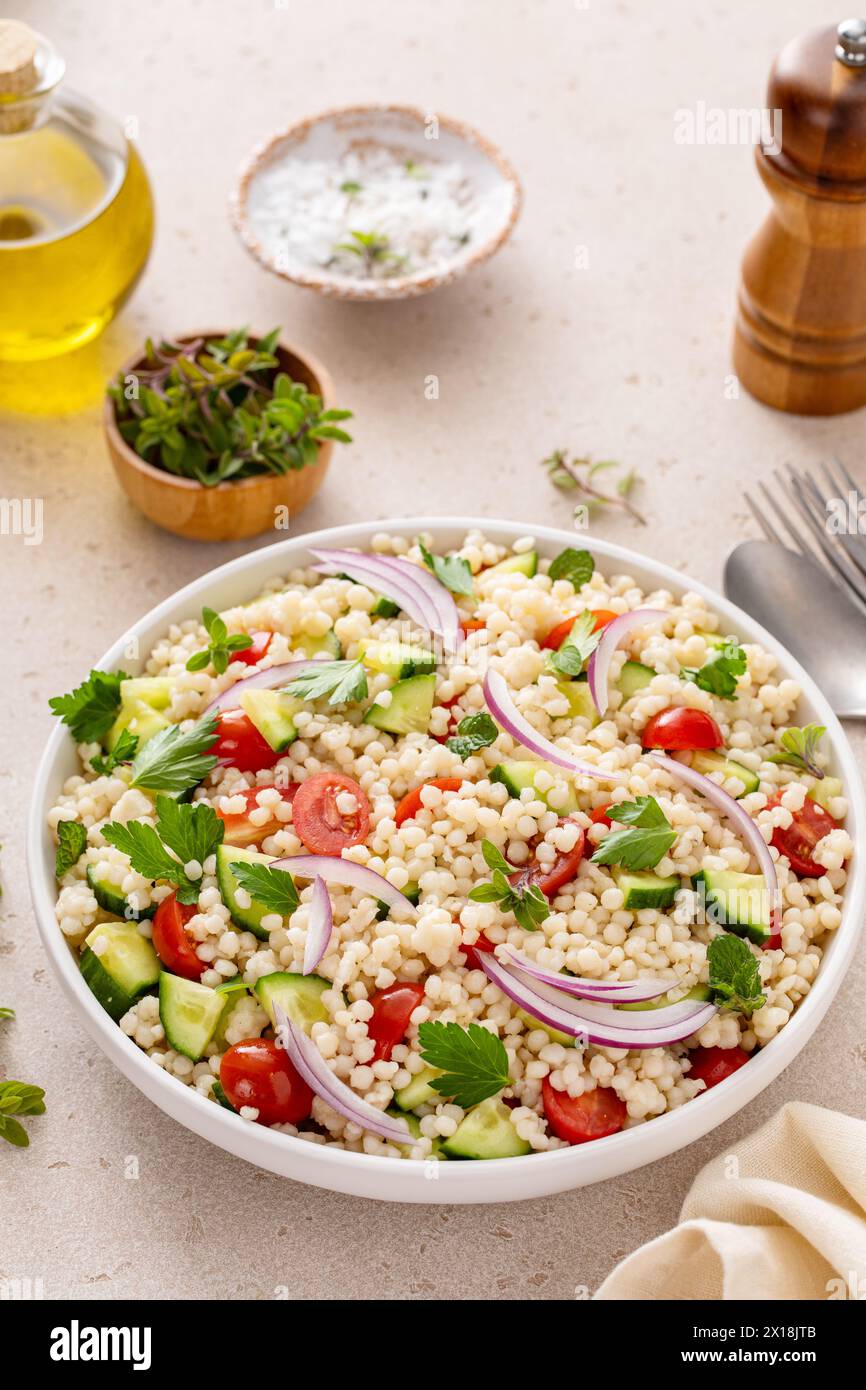 Salade de couscous perle avec des légumes frais et des herbes dans un bol de service, idée de plat d'accompagnement sain Banque D'Images