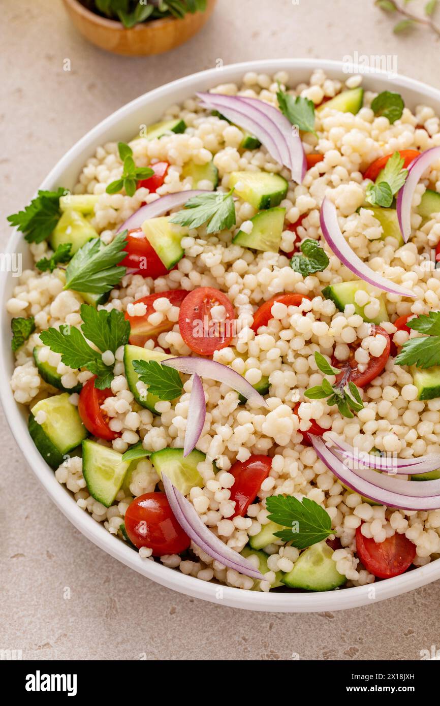 Salade de couscous perle avec des légumes frais et des herbes dans un bol de service, idée de plat d'accompagnement sain Banque D'Images