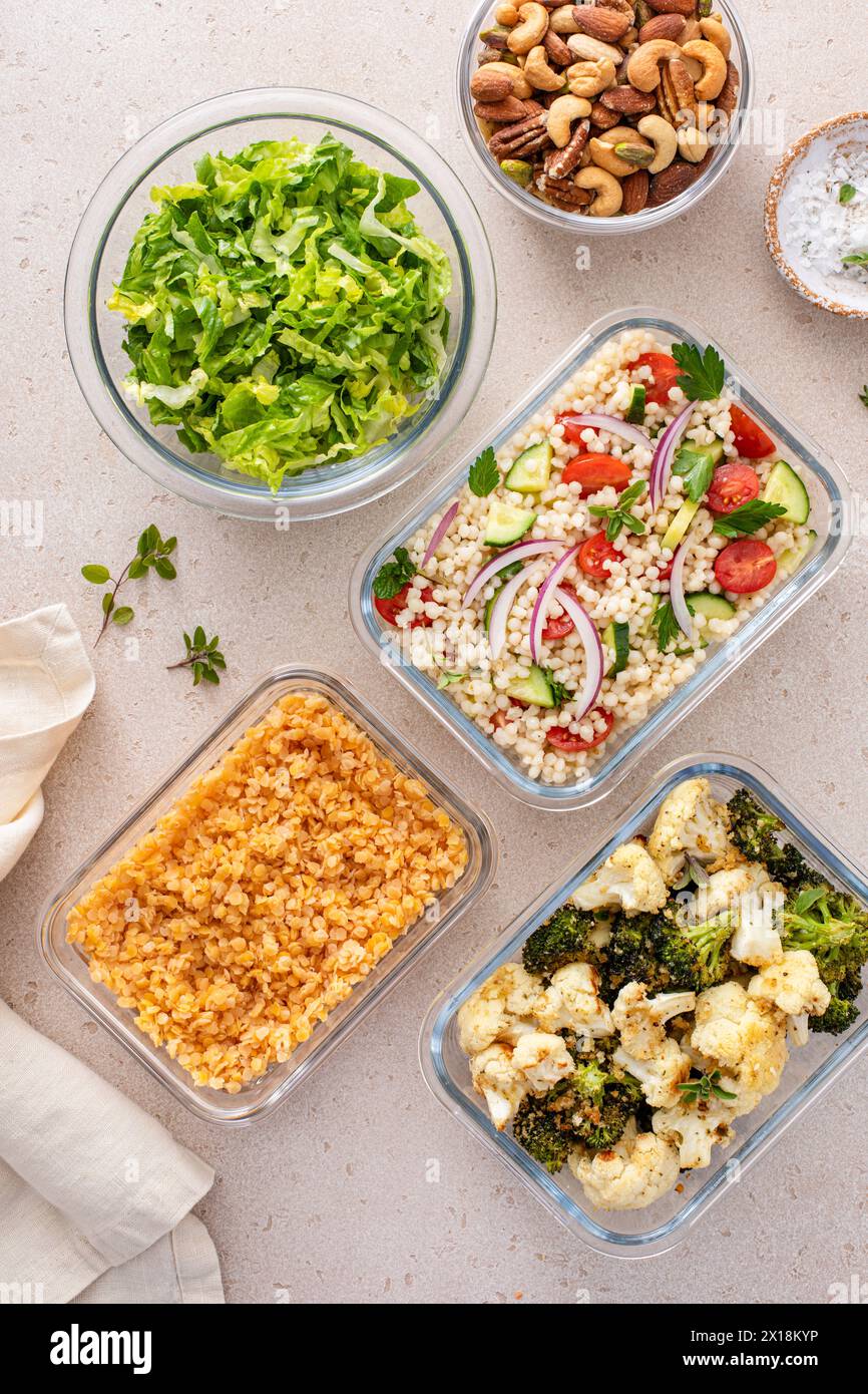 Préparation de repas végétaliens sains avec légumes rôtis, lentilles cuites, salade de couscous et noix mélangées Banque D'Images