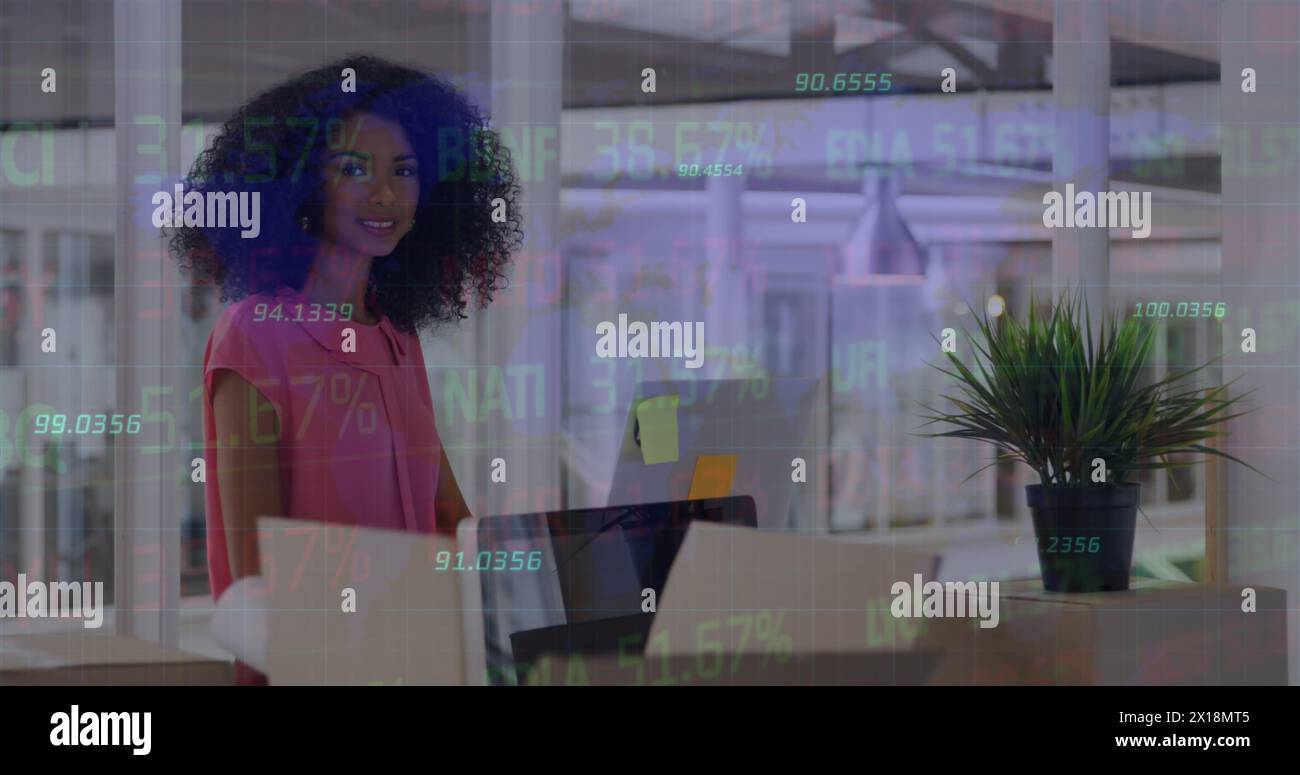 Image du traitement des données boursières sur une femme afro-américaine utilisant un ordinateur au bureau Banque D'Images