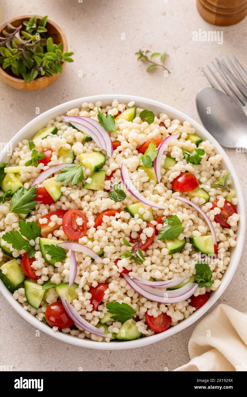 Salade de couscous perle avec des légumes frais et des herbes dans un bol de service, idée de plat d'accompagnement sain Banque D'Images