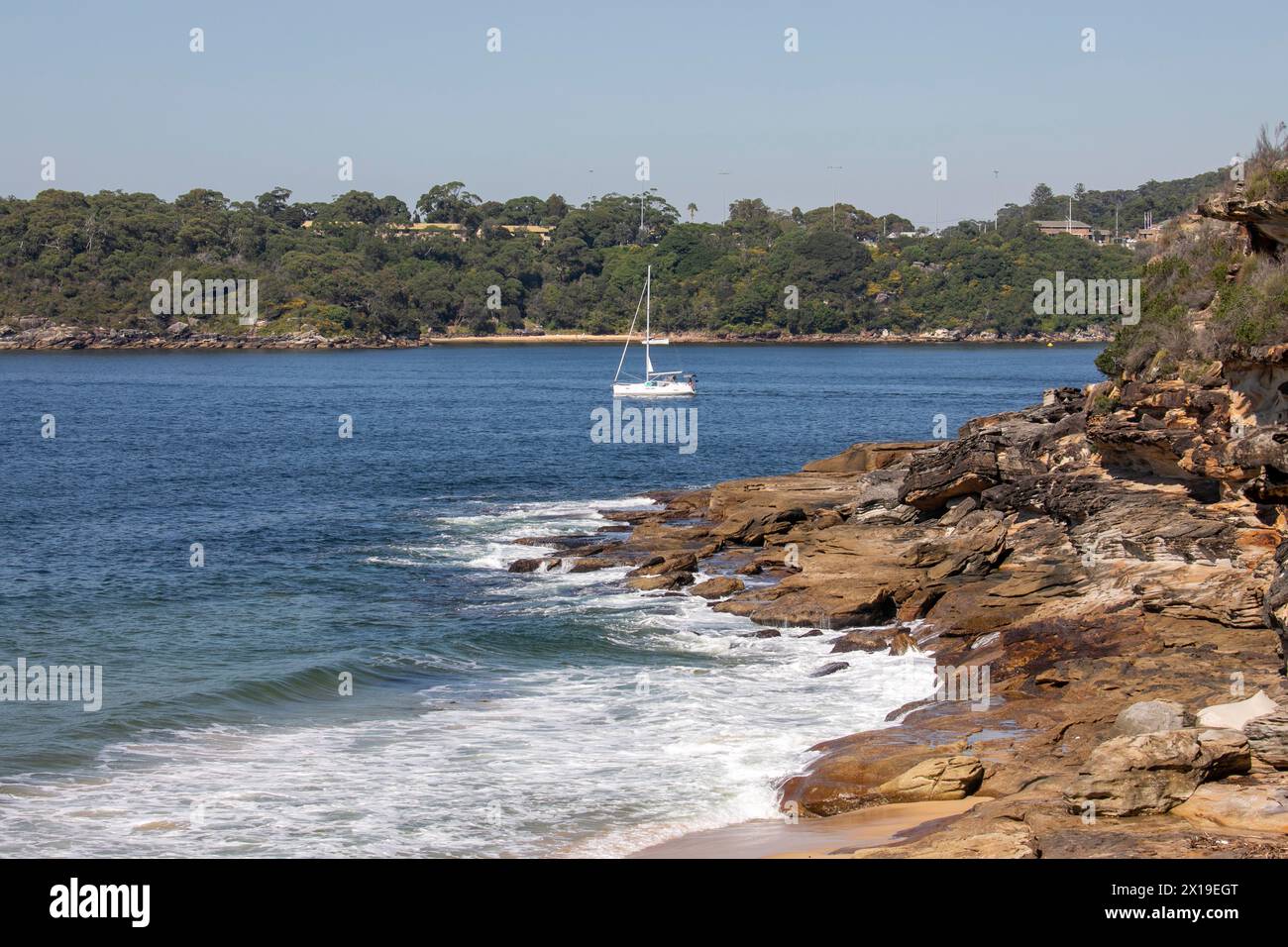 Côte du port de Sydney, plage de Cobblers sur Middle Head avec voile en yacht passé, vue depuis la plage de Wshaway sur Dobroyd Head, Sydney, Australie Banque D'Images